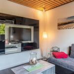 Wohnzimmer mit Sofa, Fernseher und Tisch. Decke aus Holz, Wandbild und Stehlampe.