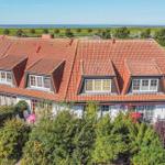 Haus mit rotem Ziegeldach und Gartenterrasse, Blick auf Grünflächen und Meer.