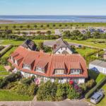 Haus mit rotem Dach, Garten und Blick auf Strand und Meer.