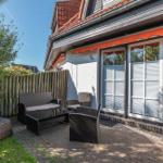 Terrasse mit Gartenmöbeln, Sitzgelegenheiten und Holzzaun. Haus mit Fenstern und Dach.