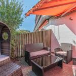 Terrasse mit Rattanmöbeln, Sonnenschutz und Gartenzaun. Hausnummer 5a an der Wand.