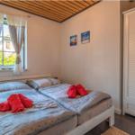 Zimmer mit Doppelbett, Fenster mit Vorhängen und weißen Schwebetüren.