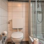 Badezimmer mit Toilette und Dusche mit Glaswand