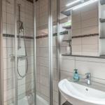 Duschkabine mit Glaswand, Waschbecken und Spiegelschrank mit Ablageflächen.