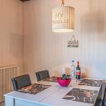 Esszimmer mit Tisch, Stühlen und Deckenleuchte. Wanddekoration und Heizung sind sichtbar.