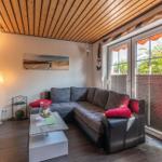 Wohnzimmer mit Ecksofa, Fernseher und Blick auf Garten.