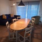 Esszimmer mit Holztisch, Stühlen und Sofa. Fenster mit blauen Vorhängen.