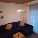 Ein Wohnzimmer mit blauem Sofa, Holztisch und Vorhängen.