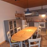 Küche mit Essbereich, Holztisch, weißen Stühlen und grauen Schränken.