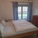 Schlafzimmer mit Bett, Schrank und Fenster zur Außenterrasse.