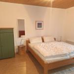 Schlafzimmer mit Holzbett, grünem Schrank und Spiegel an der Wand.