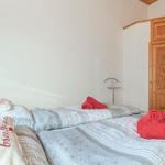 Schlafzimmer mit Bett, roten Handtüchern und Holztür.