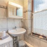 Badezimmer mit Waschbecken, Spiegel, Fenster und Waschmaschine.