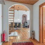 Haus mit Holzdecke, Tür und Sicht auf Esszimmer mit Holzboden und Kaminofen.