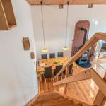 Von oben: Holztreppe, Essbereich mit Tisch und Stühlen, Kaminofen und Wohnbereich.
