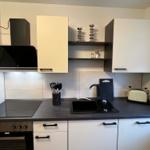 Küche mit Dunstabzug, Herd, Spüle und weißen Schränken.