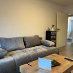 Wohnzimmer mit Sofa, Couchtisch und Blick in die Küche.