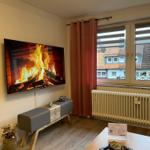 Wohnzimmer mit Fernseher, Fenster und Heizkörper