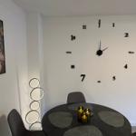 Esszimmer mit runder Tisch, Kerzen und Wanduhr mit Ziffern.