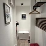 Eingangsbereich mit Kleiderständer, rotem Hocker und weißem Schrank.