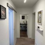 Flur mit Holzboden, Wandbildern und Blick in die Küche.