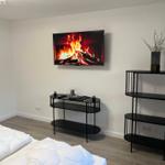 Schlafzimmer mit Bett, Fernseher und schwarzen Regalen.