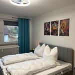 Schlafzimmer mit Bett, Fenster und Wandbildern.