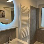 Badezimmer mit Waschbecken, Spiegel und Dusche.