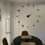 Esszimmer mit runder Tisch, gelben Stühlen und Wanduhr mit Ziffern.