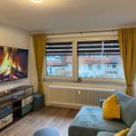 Wohnzimmer mit Sofa, Fernseher und Fenster mit Blick auf Gebäude.