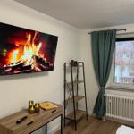 Wohnzimmer mit Fernseher, Schrank und Fenster mit Vorhang.