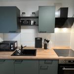 Küche mit Holz Arbeitsplatte, Dunstabzug, Herd und Mikrowelle.