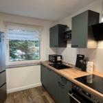 Küche mit dunklen Schränken, Holz Arbeitsplatte und Fenster mit Blick auf Bäume.