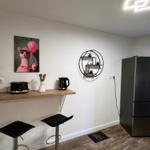 Küche mit Barhocker, Kühlschrank und Wandregal.