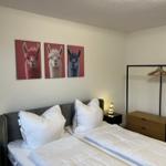 Schlafzimmer mit Doppelbett, Wandbildern von Lamas und Kleiderschrank.