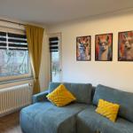 Ein Wohnzimmer mit blauem Sofa, gelben Kissen und drei Wandbildern von Lamas.