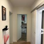 Flur mit Holzboden, Wandbild und Blick in Küche mit Barhocker.