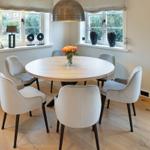 Runder Esstisch mit sechs Stühlen, Fenster und Lampe im Esszimmer.