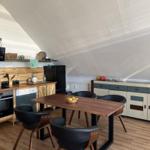 Kitchen with dining area under sloped ceilings, wooden surfaces, and modern furniture.