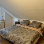 Bedroom with sloped ceiling, wooden floor, and bed with patterned bedding.