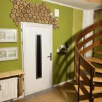 Entrance area with spiral staircase, green wall, and wood decor.