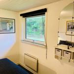 A bedroom with bed, window, heater, and mirrored cabinet.
