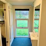 Hallway with blue carpet, window to greenery, and mirrored wall.