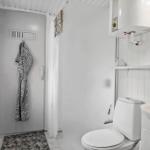 Bathroom with toilet, sink, and shower. White walls and a gray rug.