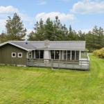 A house with green cladding and large veranda in the grassland.