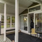 Deck with seating area and glass door to house. Wooden floor and garden in background.