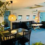 Dining area with table and chairs. Living area with sofa and coffee table. Ceiling and walls are panelled white.