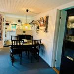 Dining room with table, chairs, and kitchen area in the background.