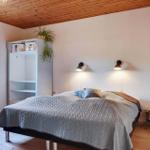 Bedroom with bed, nightstand, wardrobe, and window. Wooden ceiling and floor.