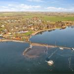Aerial view of a harbor with boats and surrounding houses by a lake.
